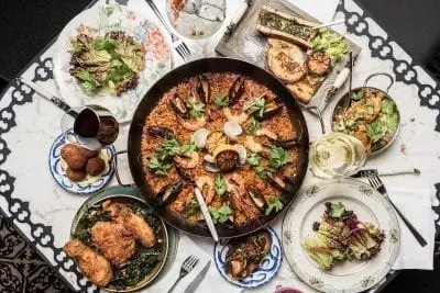 overhead photo of paella dish and side salads