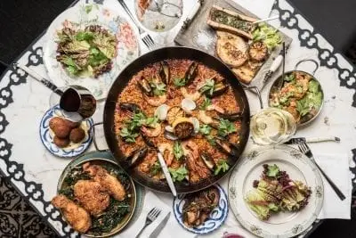 overhead shot of paella dish in the center and smaller side dishes surrounding it