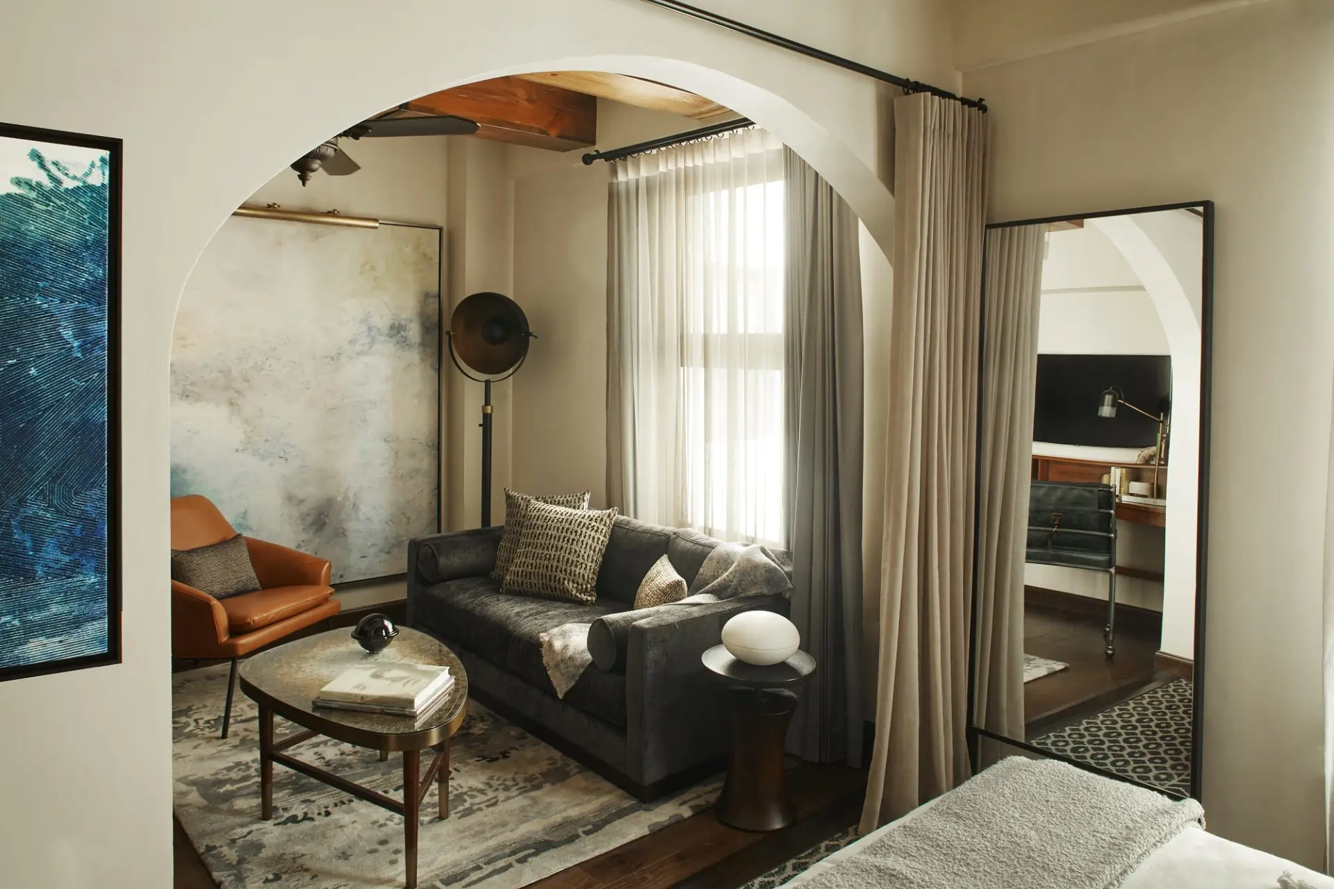 hotel suite living room with furniture and large mirror in bedroom