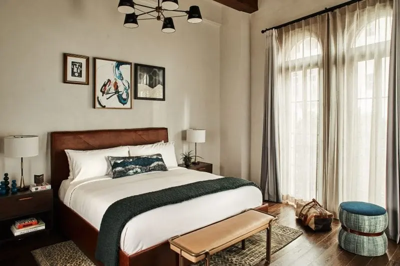 hotel room with bed, nightstands, arched windows and ottoman