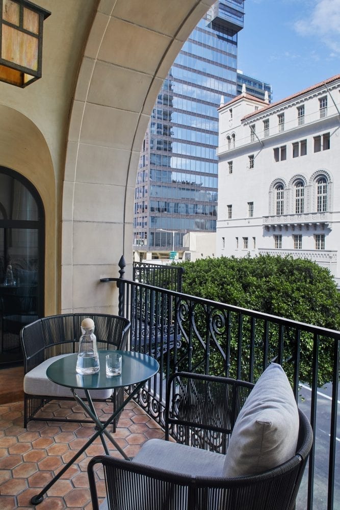 two chairs and a table on a balcony overlooking buildings