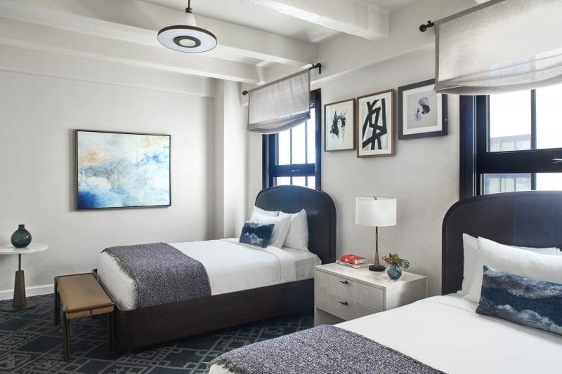 hotel room with two beds, nightstand and framed art