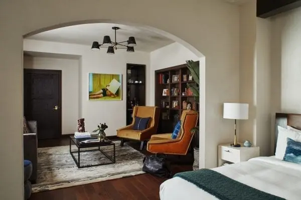 hotel suite with view from bedroom to living room with chairs and coffee table