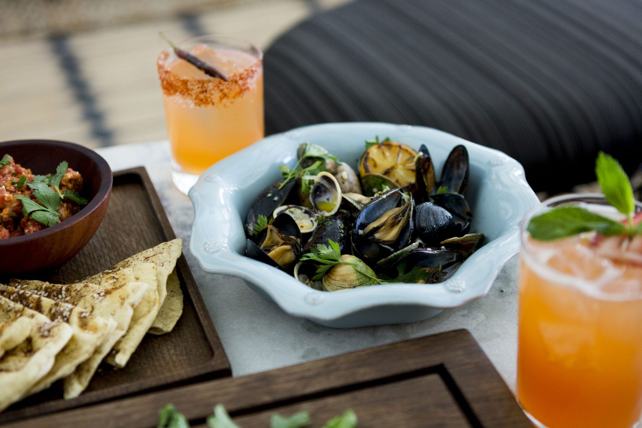table with bowl with clams, cocktails and salsa