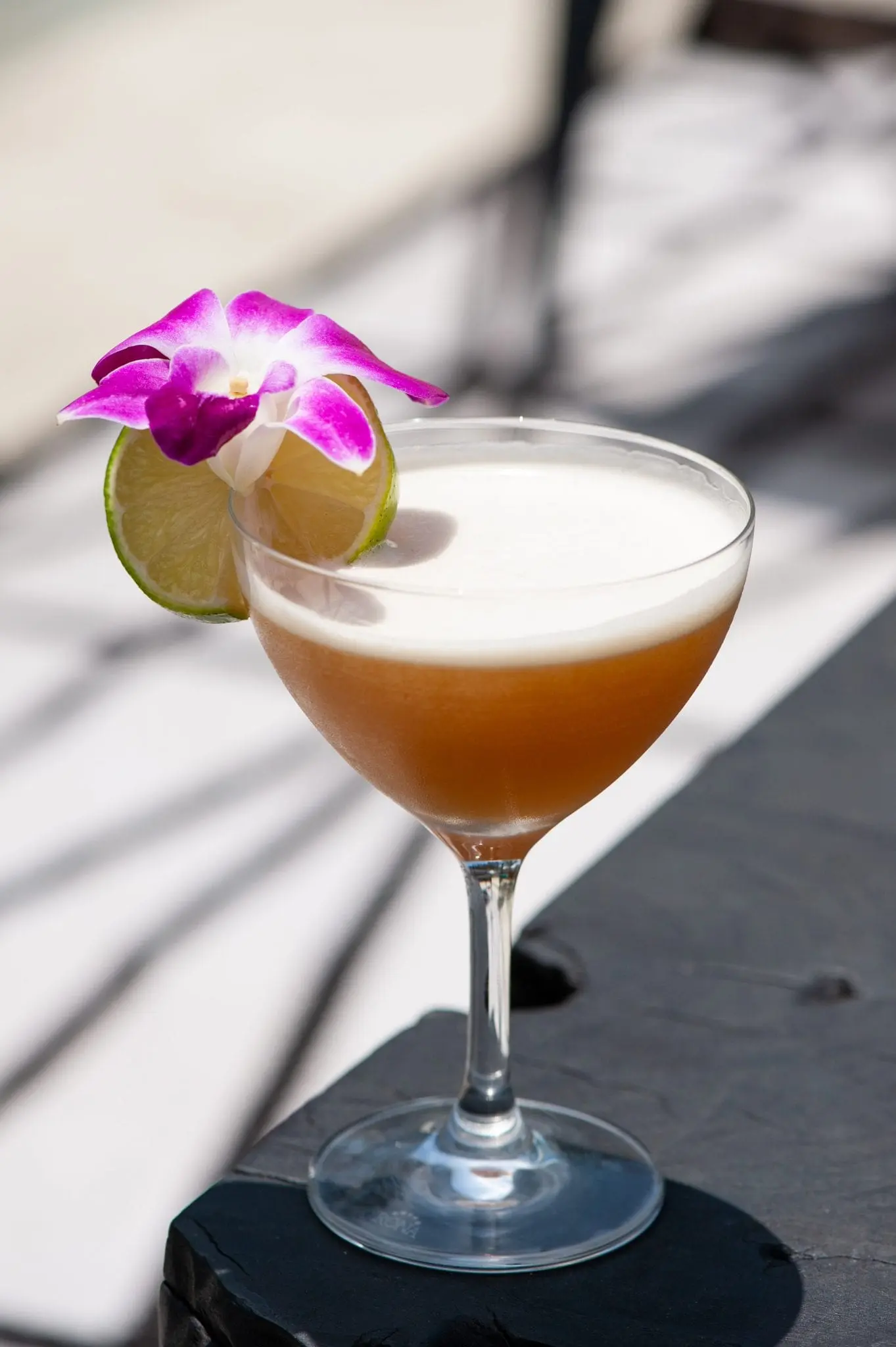 blood and sand cocktail in martini glass with slice of lime and flower