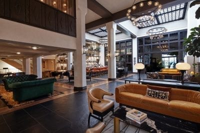 hotel lobby with sofa, chairs, high ceiling and bar in the background
