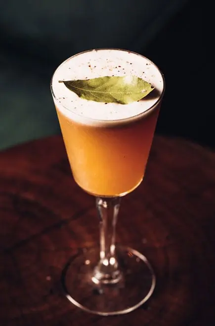 cocktail glass on table with leaf on top