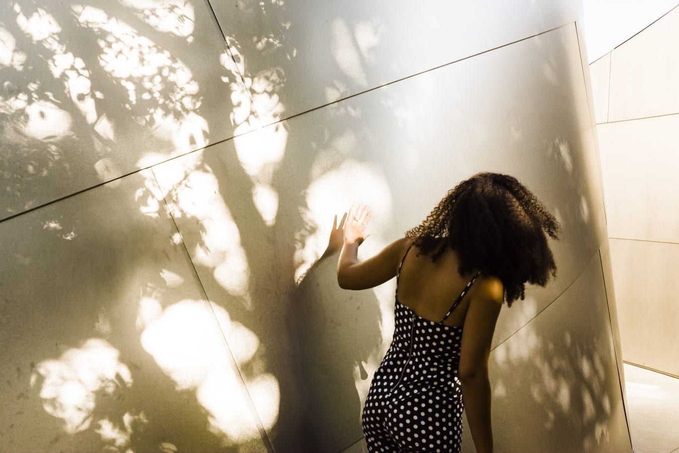 woman walking outside during the day touching a wall