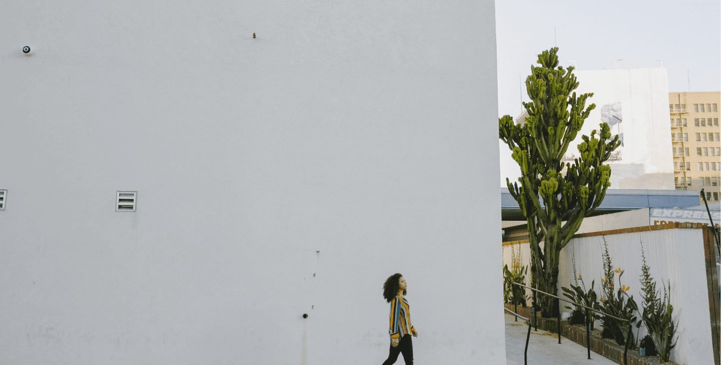 woman walking in front of large, empty building wall