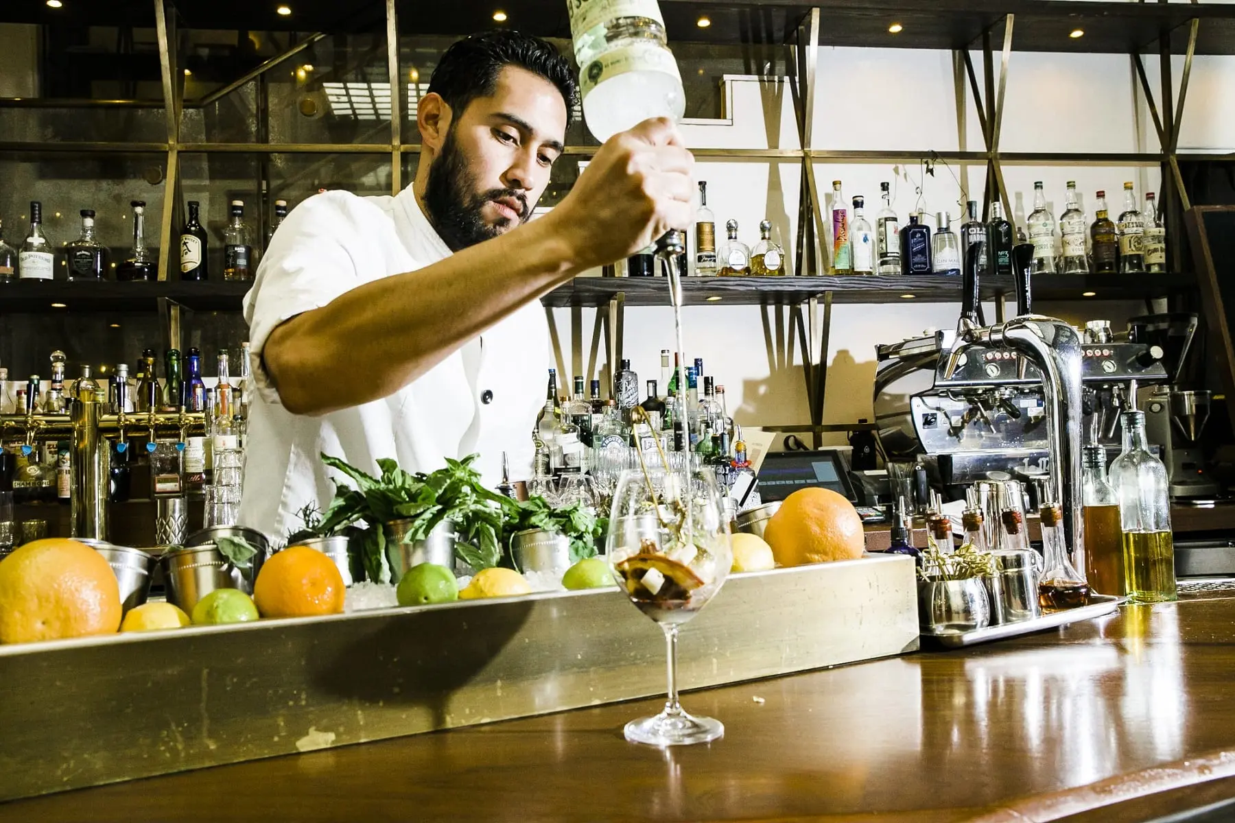 a man standing behind a bar preparing a fruit cocktail