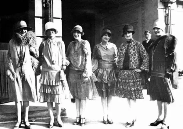 old photo of women dressed in 30s attire, posing for a photo next to each other