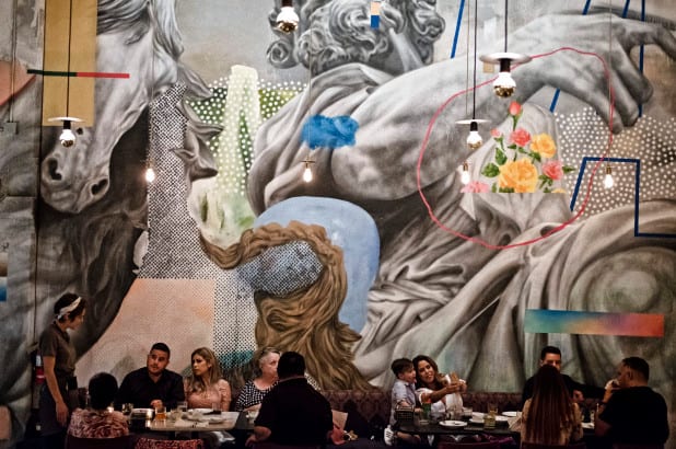 restaurant patrons sitting at tables in front of large mural
