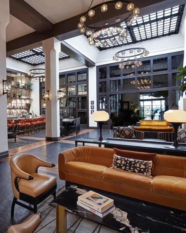 lounge area with sofa, chair, coffee table with books, and bar area in the background