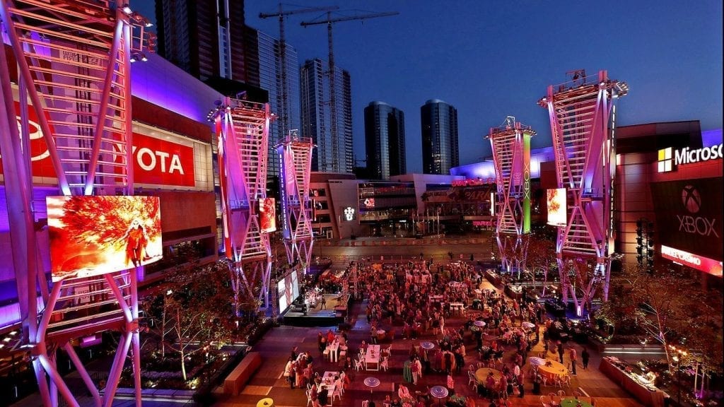 people sitting at tables outdoors at night next to buildings with lit signs