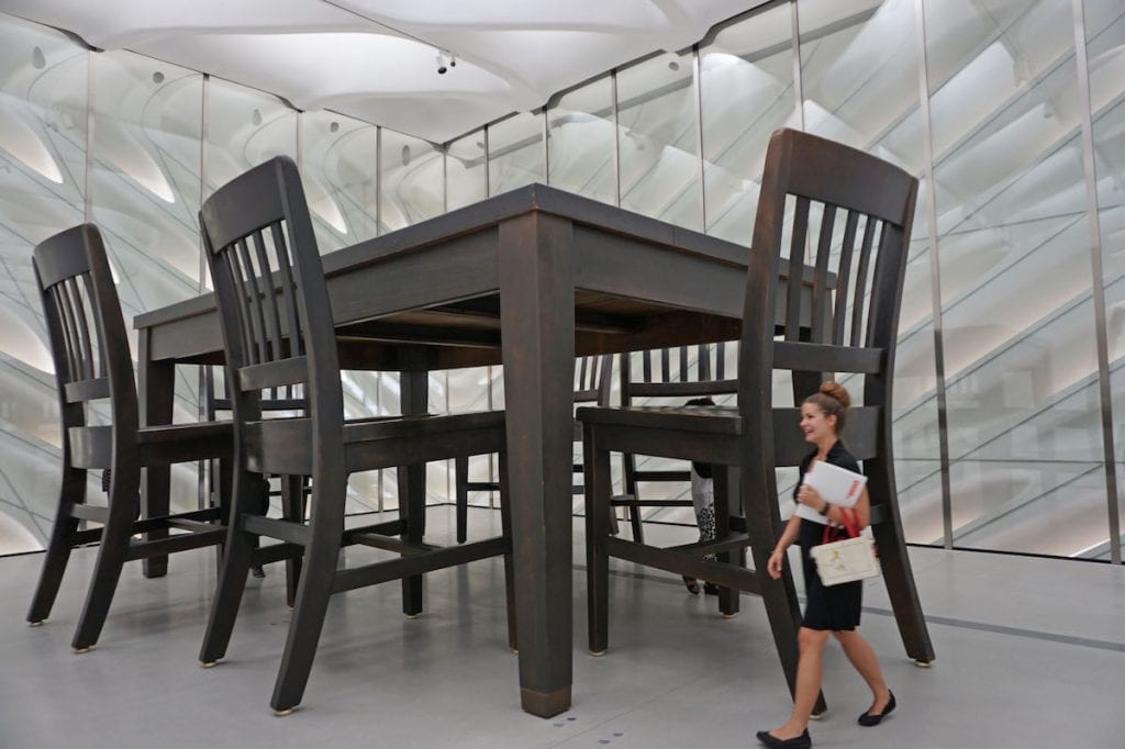 woman walking past giant dining table and chair
