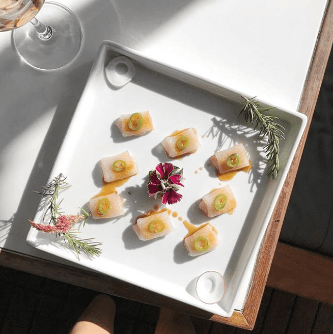 square plate with yellowtail sashimi and glass of wine