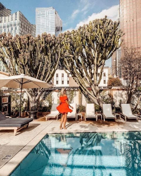 woman in red dress standing near pool