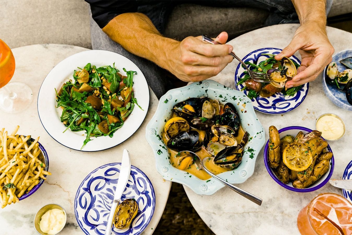 man eating oysters and various dishes on two round tables